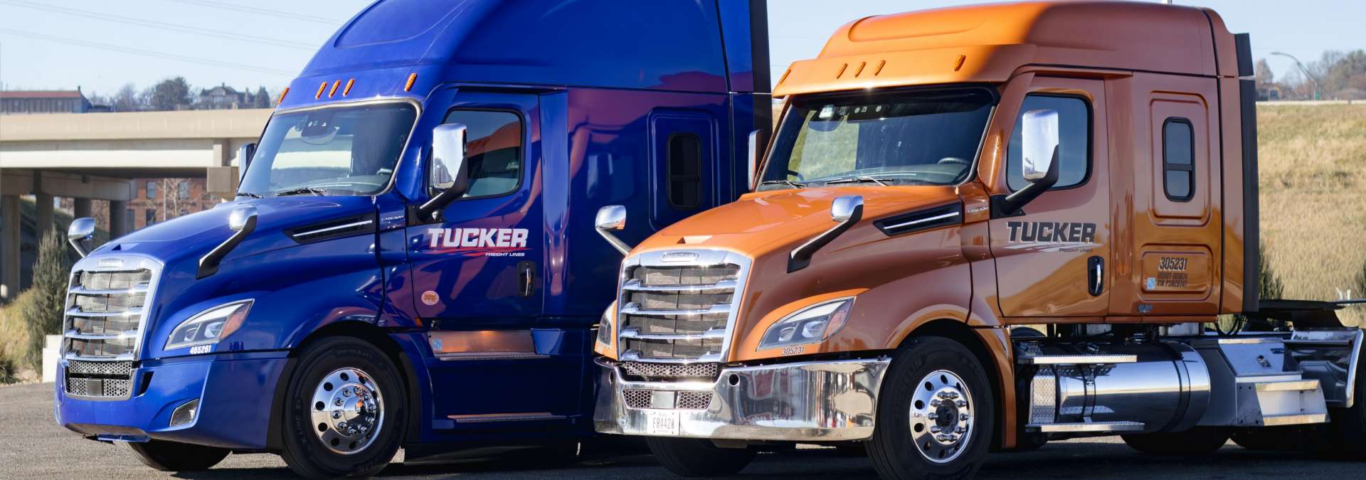 blue and orange Tucker Freight Lines Semis parked in a artful staggered line
