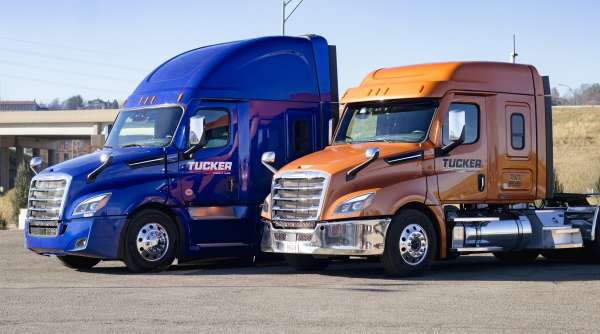 blue and orange Tucker Freight Lines Semis parked in a artful staggered line