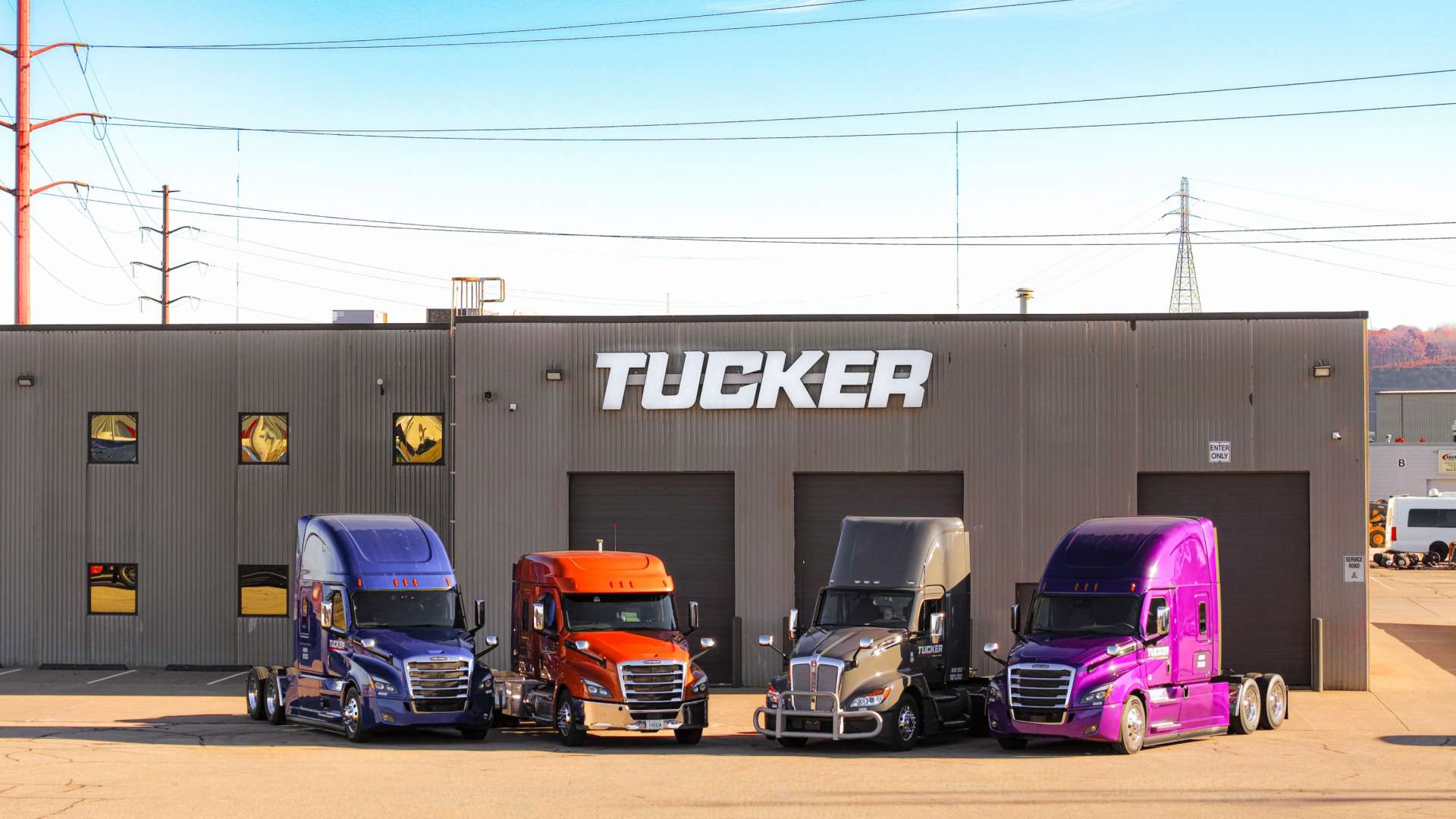 Blue, orange, grey, and purple semi trucks parked in front of the Tucker Freight Lines Dubuque, IA terminal