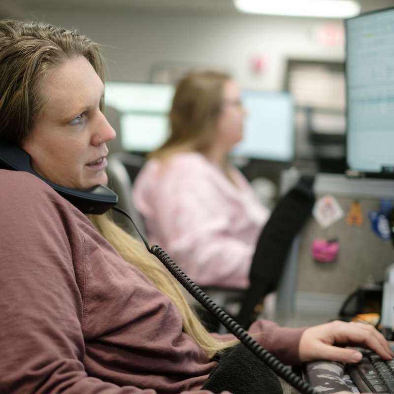 woman on phone in front of computer, typing