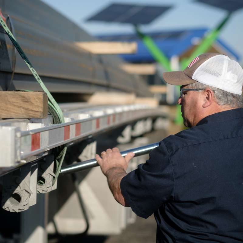 Man tightening ratchet strap on open deck semi