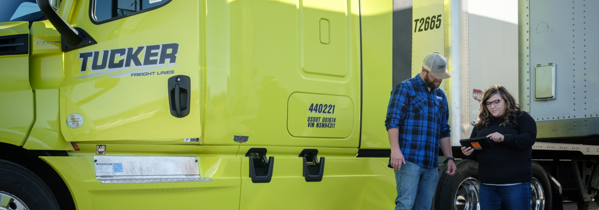 woman holding out tablet while man looks at it with hands on his hips