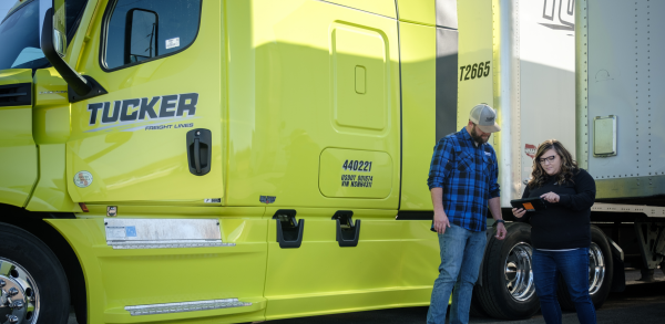 woman holding out tablet while man looks at it with hands on his hips